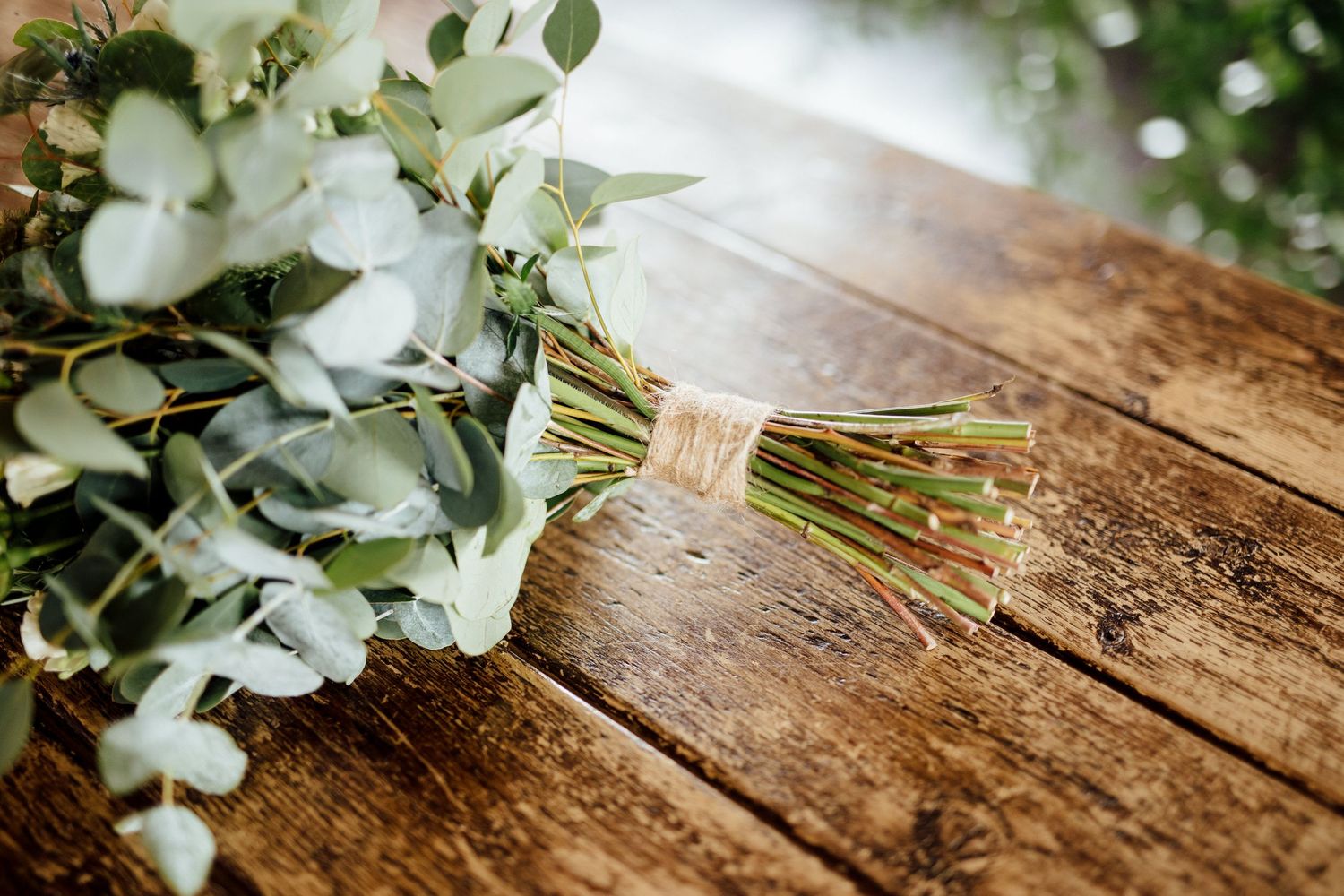 White floral arrangements with greenery displayed on rustic wooden surface.
