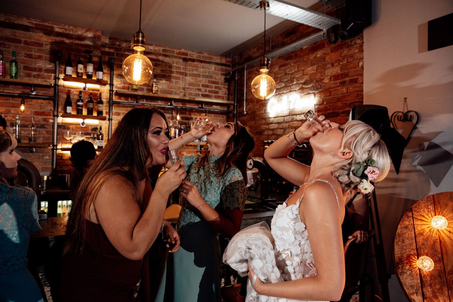 Wedding celebration in an industrial-style venue with exposed brick walls and hanging Edison bulbs.