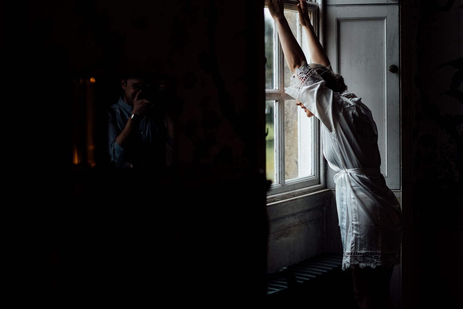 Dramatic silhouette of wedding preparations against window light.