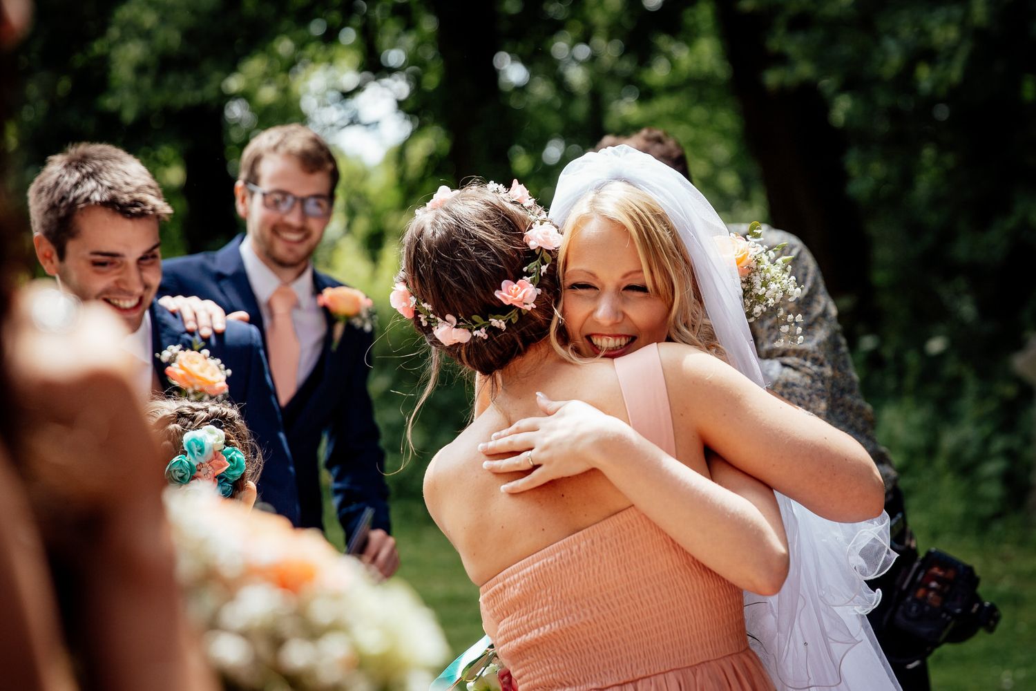 Wedding party shares emotional embraces during outdoor celebration.