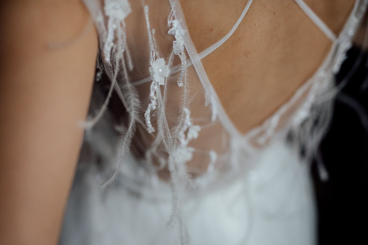Delicate lace detail of a white wedding dress against skin.