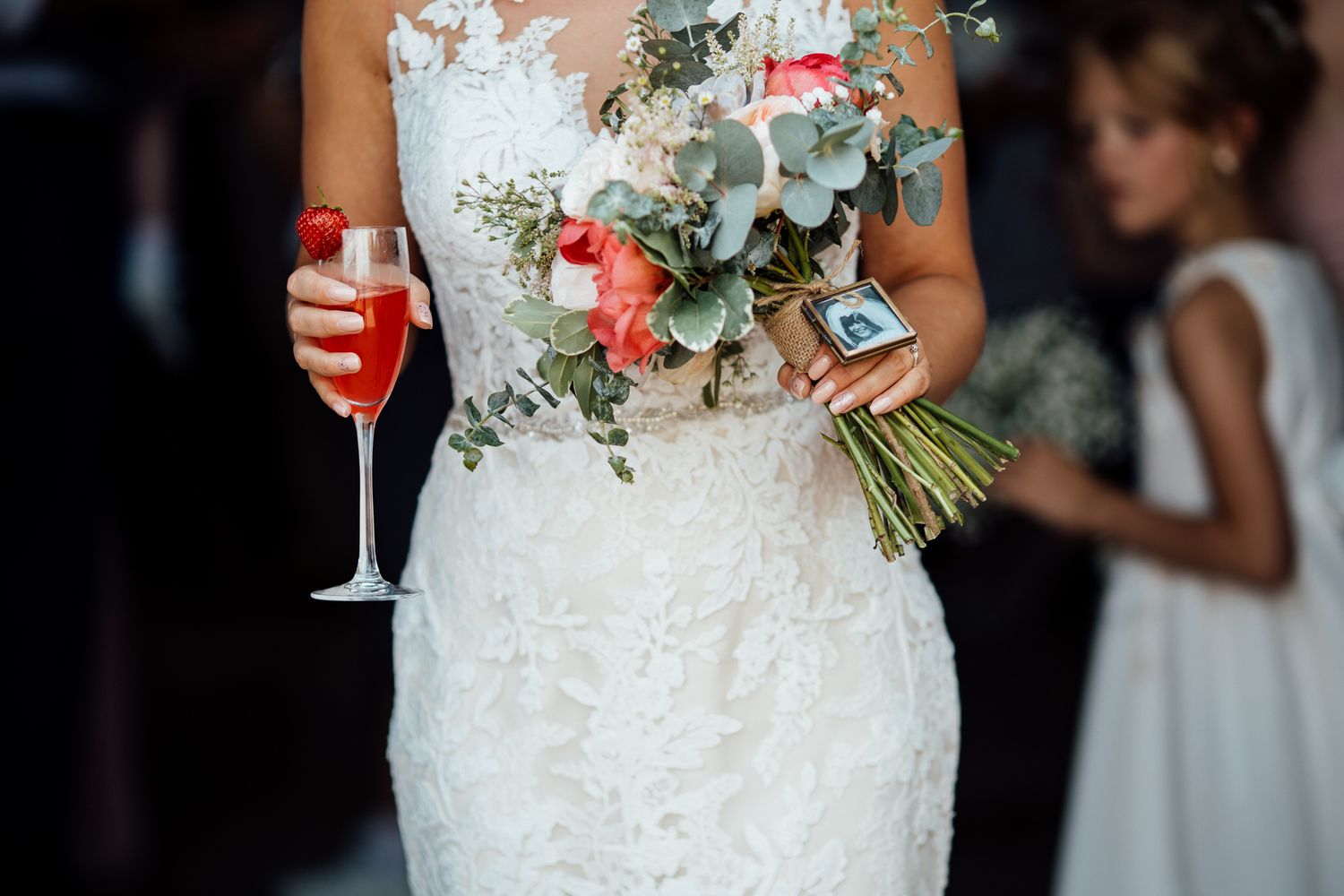 Close-up of white lace wedding dress with floral bouquet details.