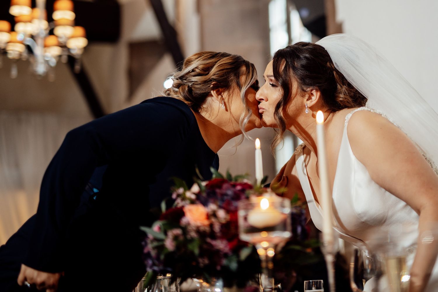 Intimate moment shared across an elegantly decorated reception table with floral centerpieces.