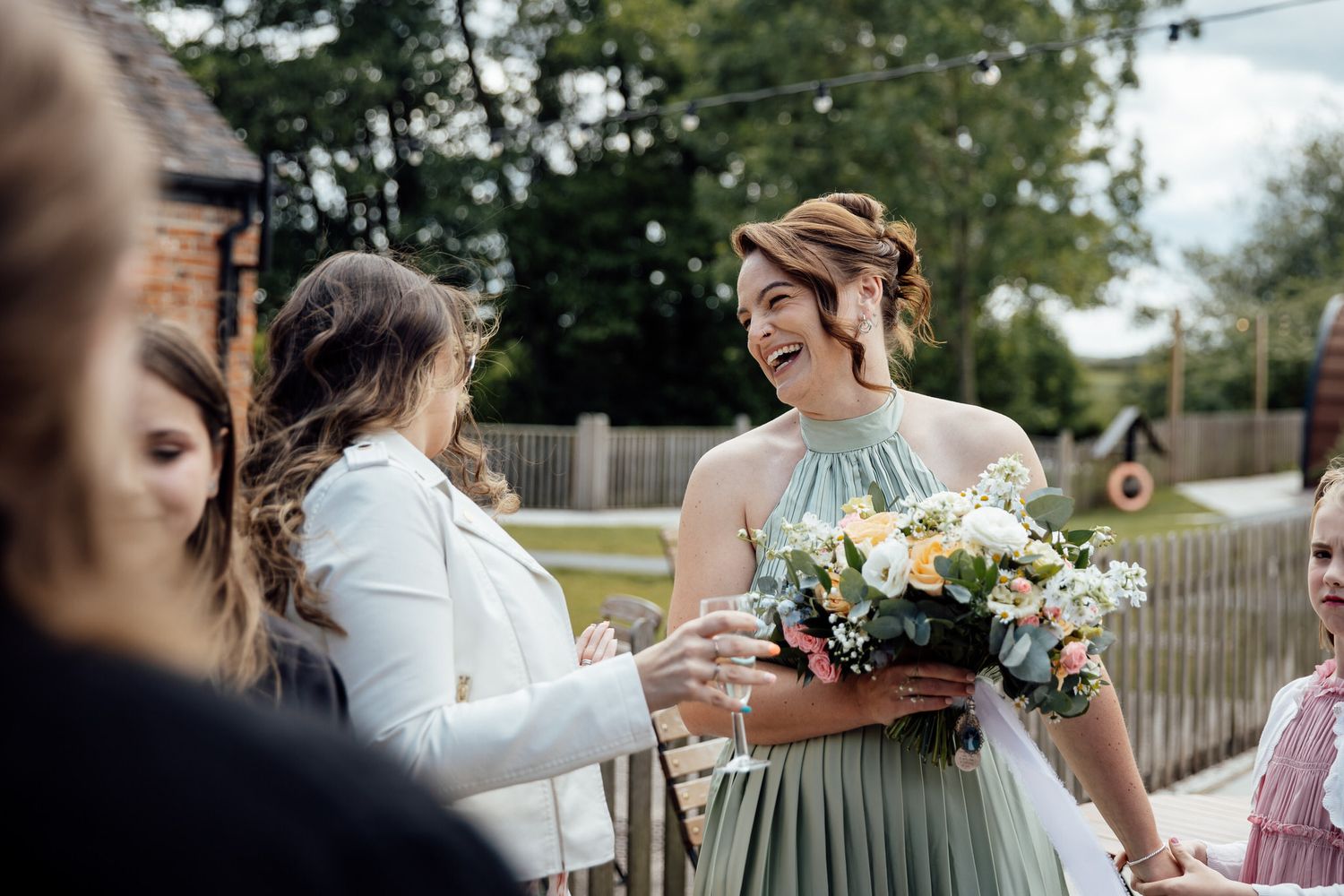 Wedding party members sharing candid moments outdoors with floral bouquets.