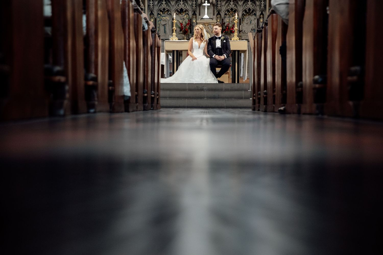 Interior view of a grand church aisle with dramatic lighting and wooden pews.