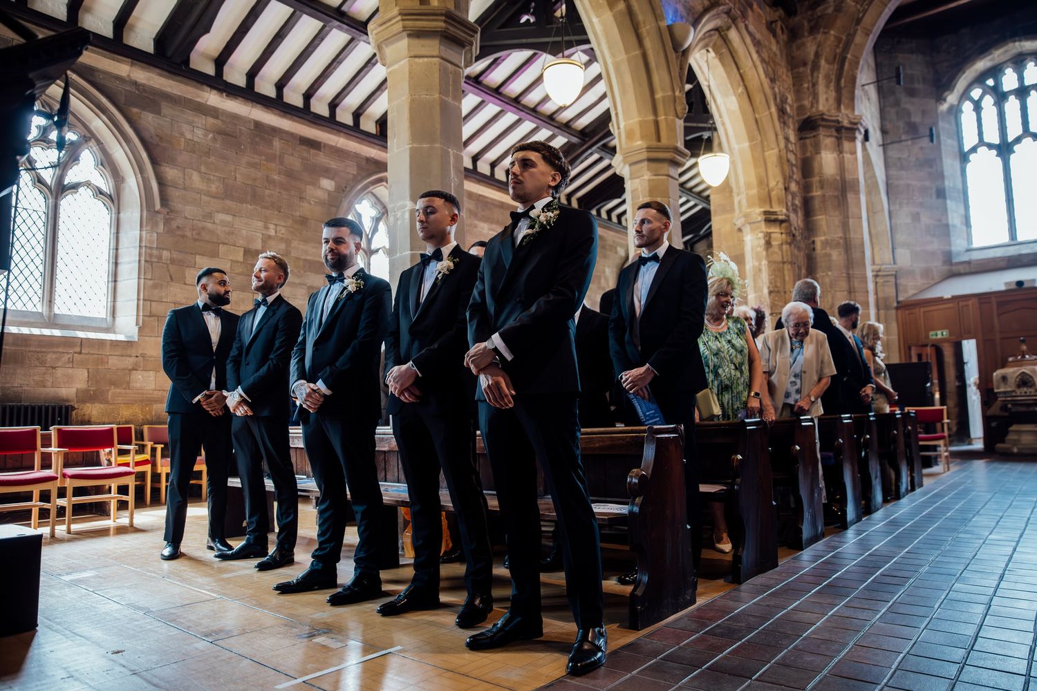 Wedding party lined up along the side of a grand church interior.