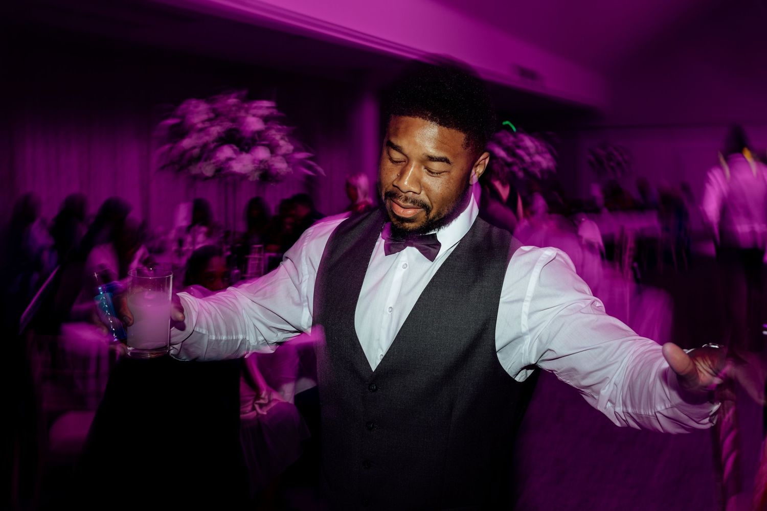 Dance floor celebration with purple mood lighting at wedding reception.