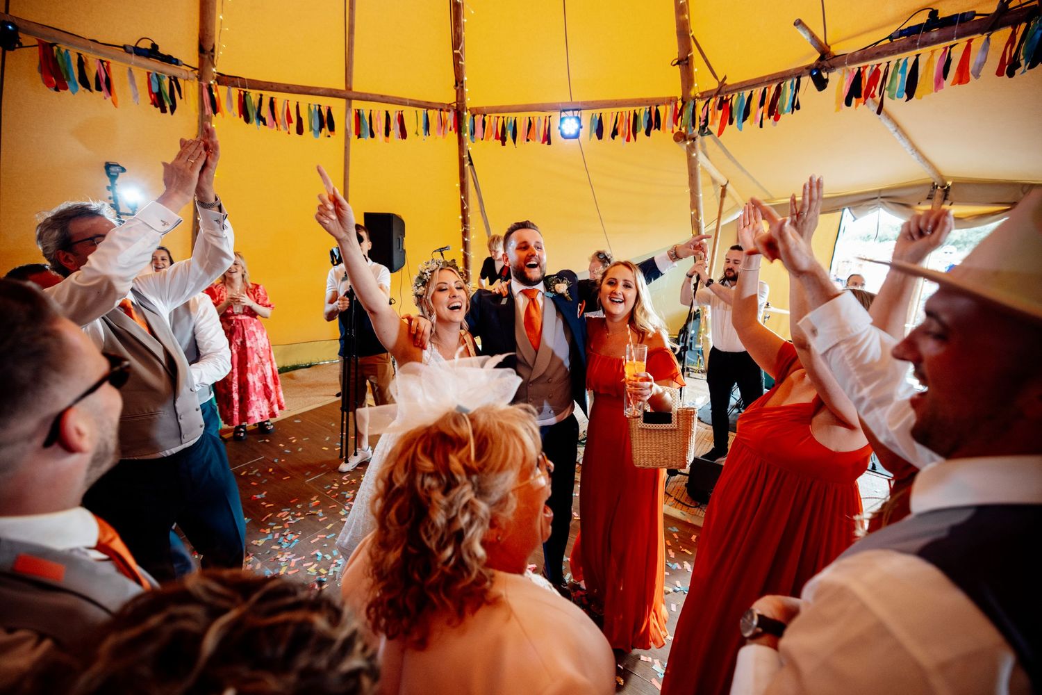 Festive reception inside a tipi tent with colorful bunting decorations and warm lighting.