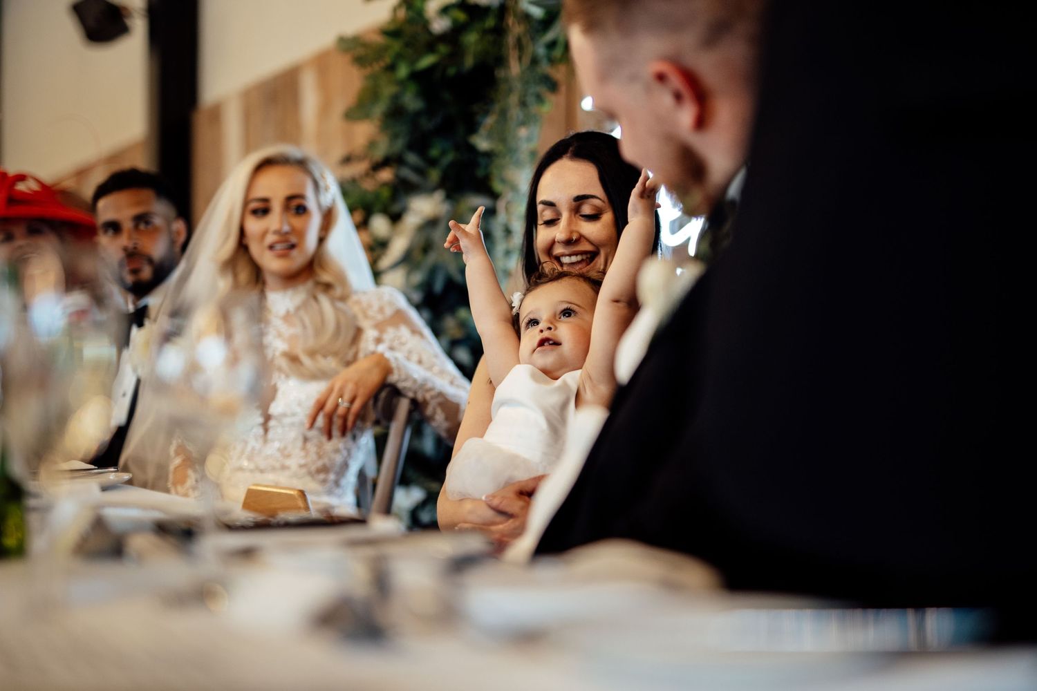 Wedding guests enjoy a festive reception celebration indoors with elegant decor and lighting.