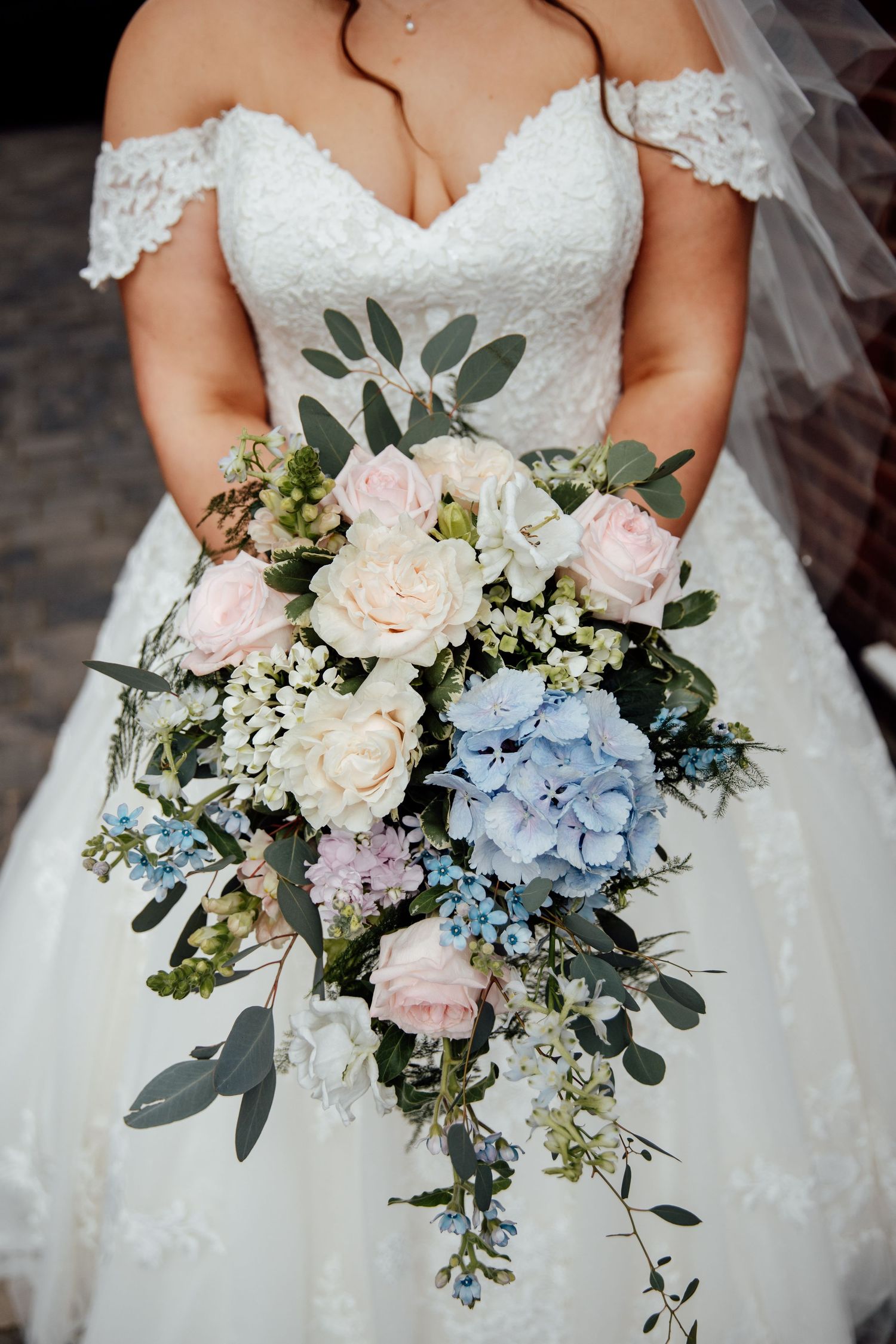 Close-up of bridal bouquet with blue hydrangeas, pink roses and eucalyptus.