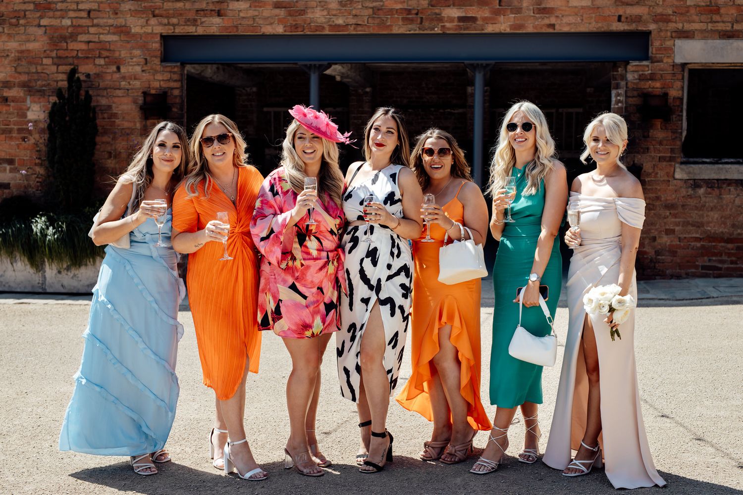 Wedding party poses together wearing colorful summer dresses and outfits.