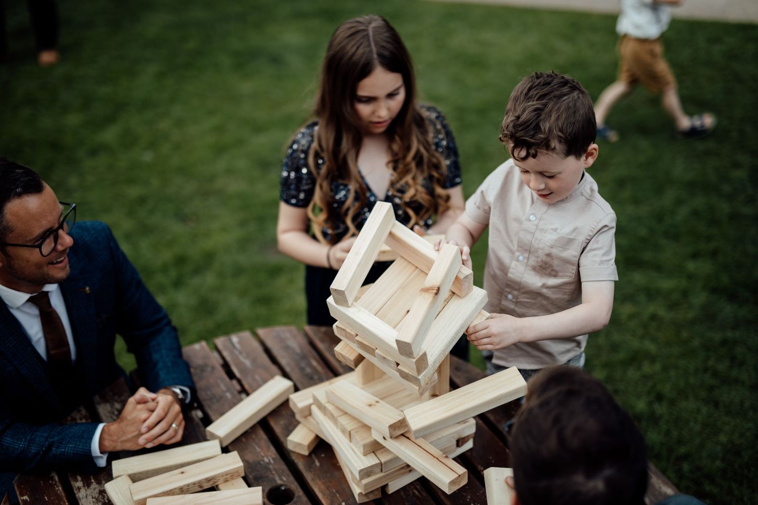 Wedding guests playing with wooden blocks during an outdoor reception game.