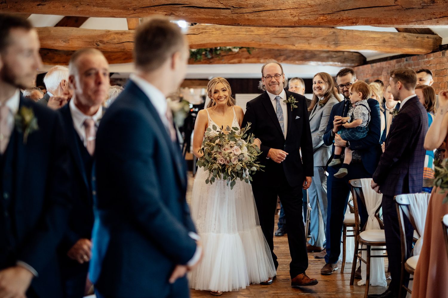 Wedding guests gathered in a rustic barn venue during a ceremony.