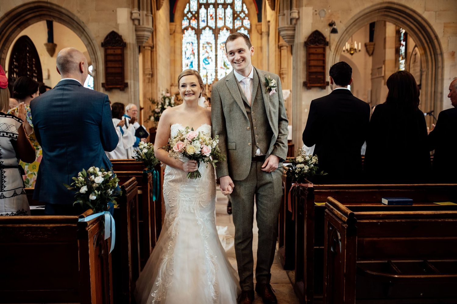 Traditional church wedding ceremony taking place in a beautiful stone chapel with stained glass windows.