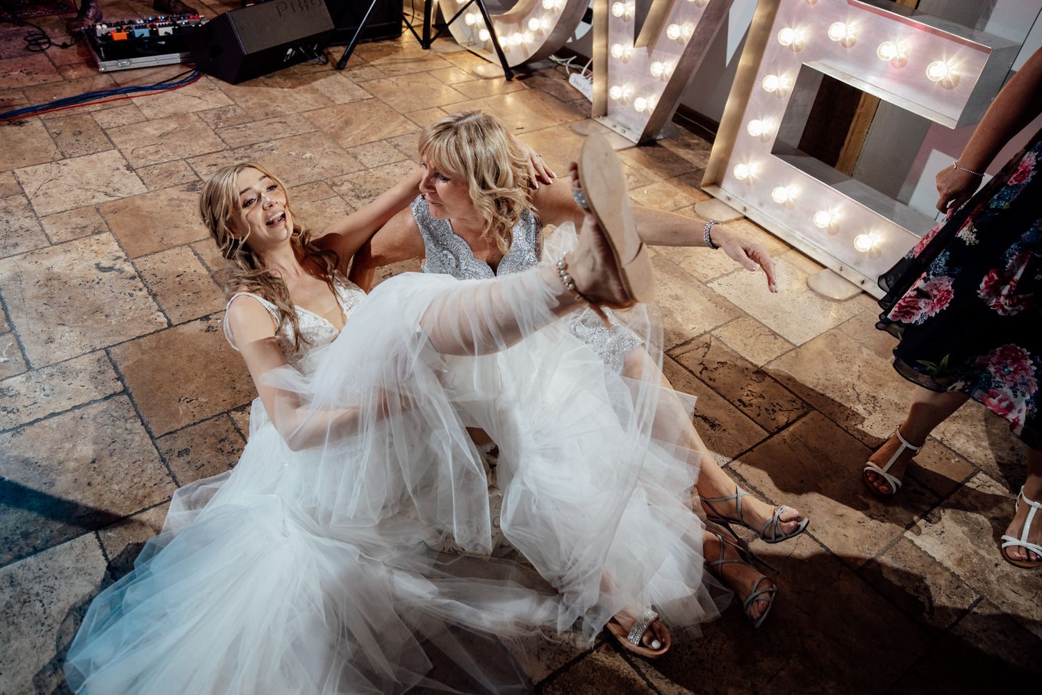 Bride in flowing white dress twirling on stone floor during reception dance.