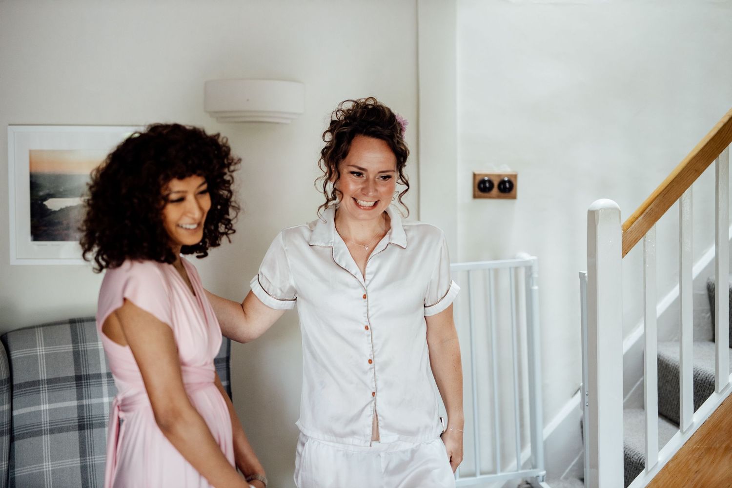 Two people share joyful moments while getting ready in a bright white room.