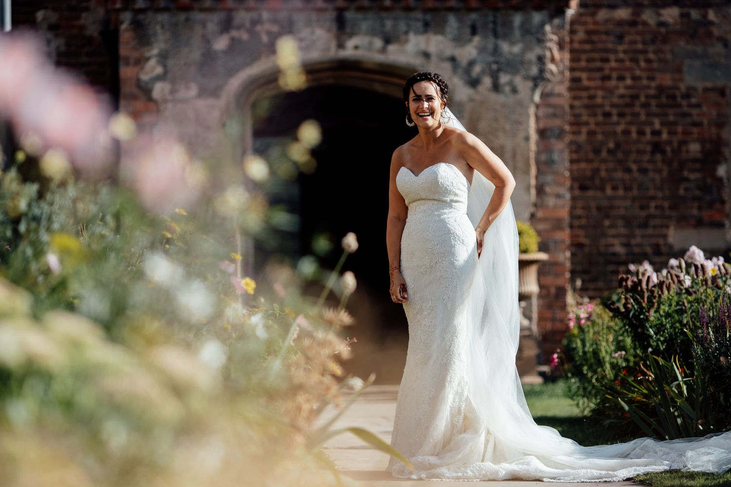 An elegant white wedding dress photographed against a rustic brick wall backdrop.