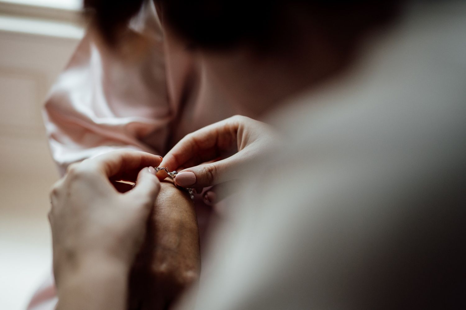Close-up shot of hands adjusting formal attire details in soft lighting.