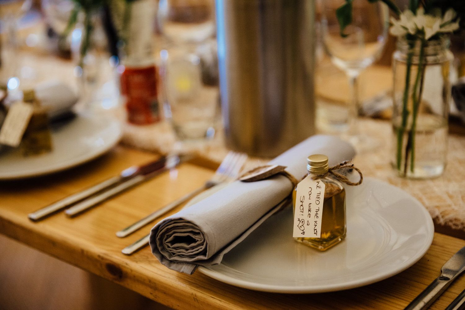Elegant wedding reception table settings with white plates and floral centerpieces.