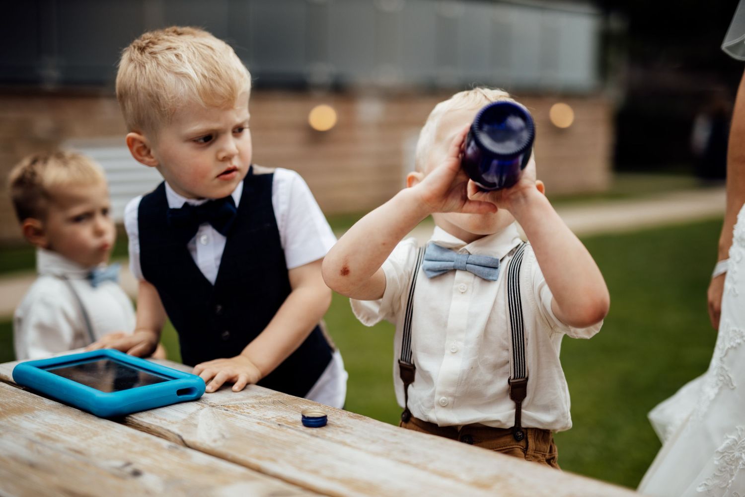 Young children in formal attire enjoy refreshments at an outdoor wedding reception.