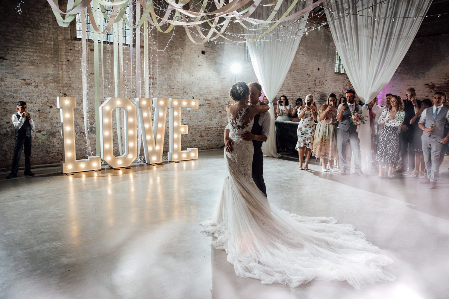 Dreamy wedding reception with fog effects and ambient lighting in an industrial venue.