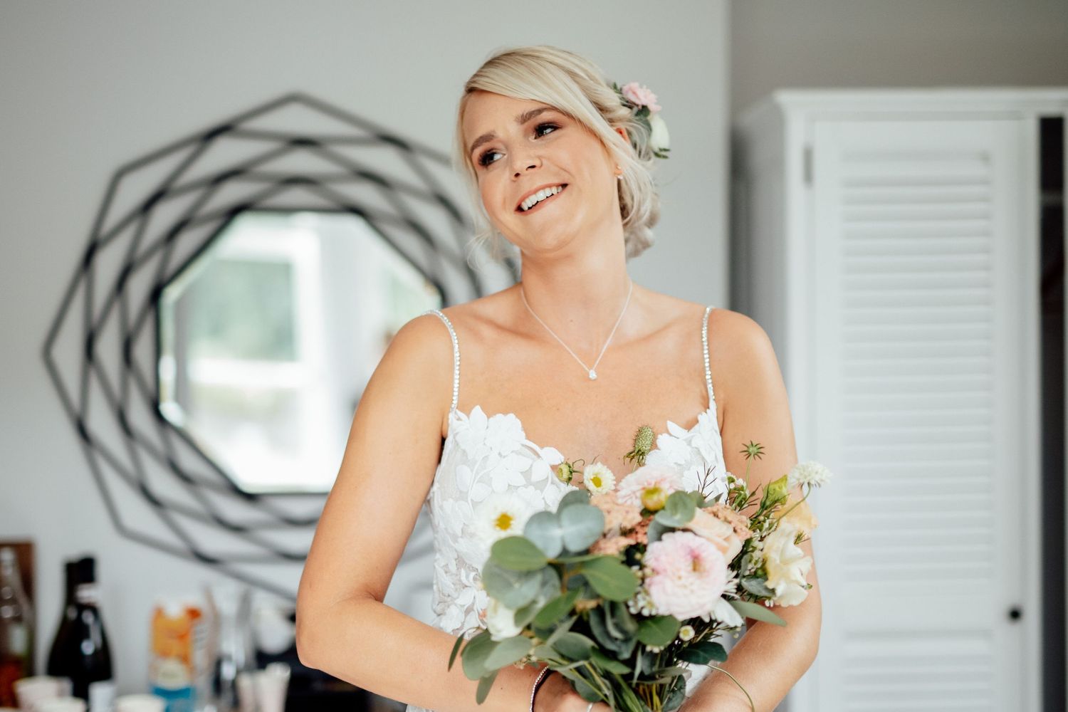 Delicate white lace wedding dress detail with floral bouquet.