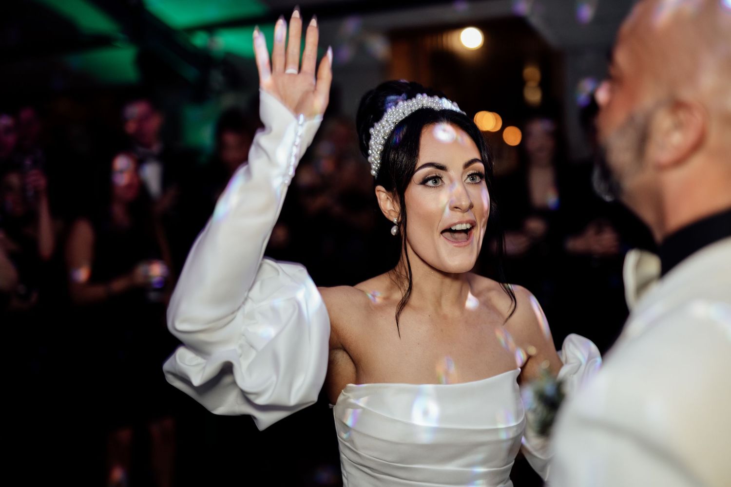 Wedding party dancing and celebrating with arms raised during an evening reception.