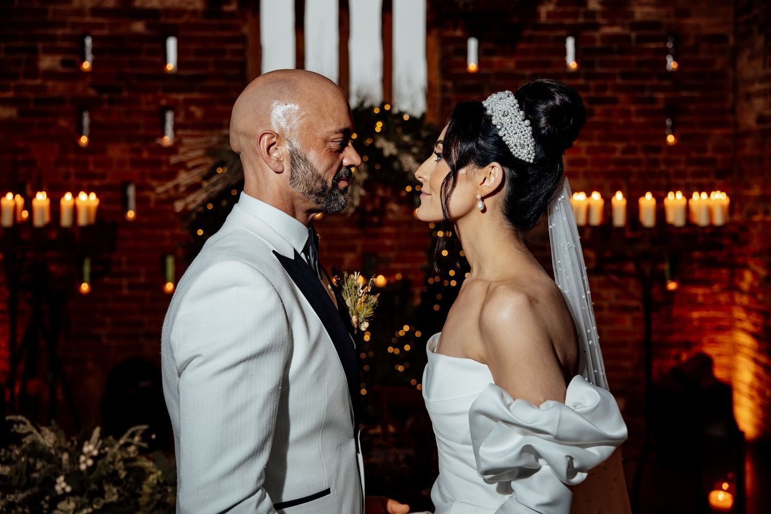 Romantic dance between couple at dimly lit reception with brick wall backdrop.