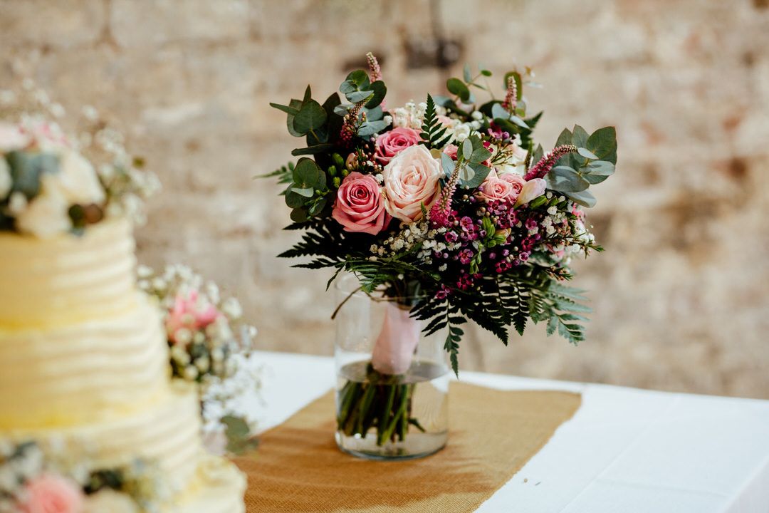 Pink and white floral arrangements with roses decorate wedding reception tables.