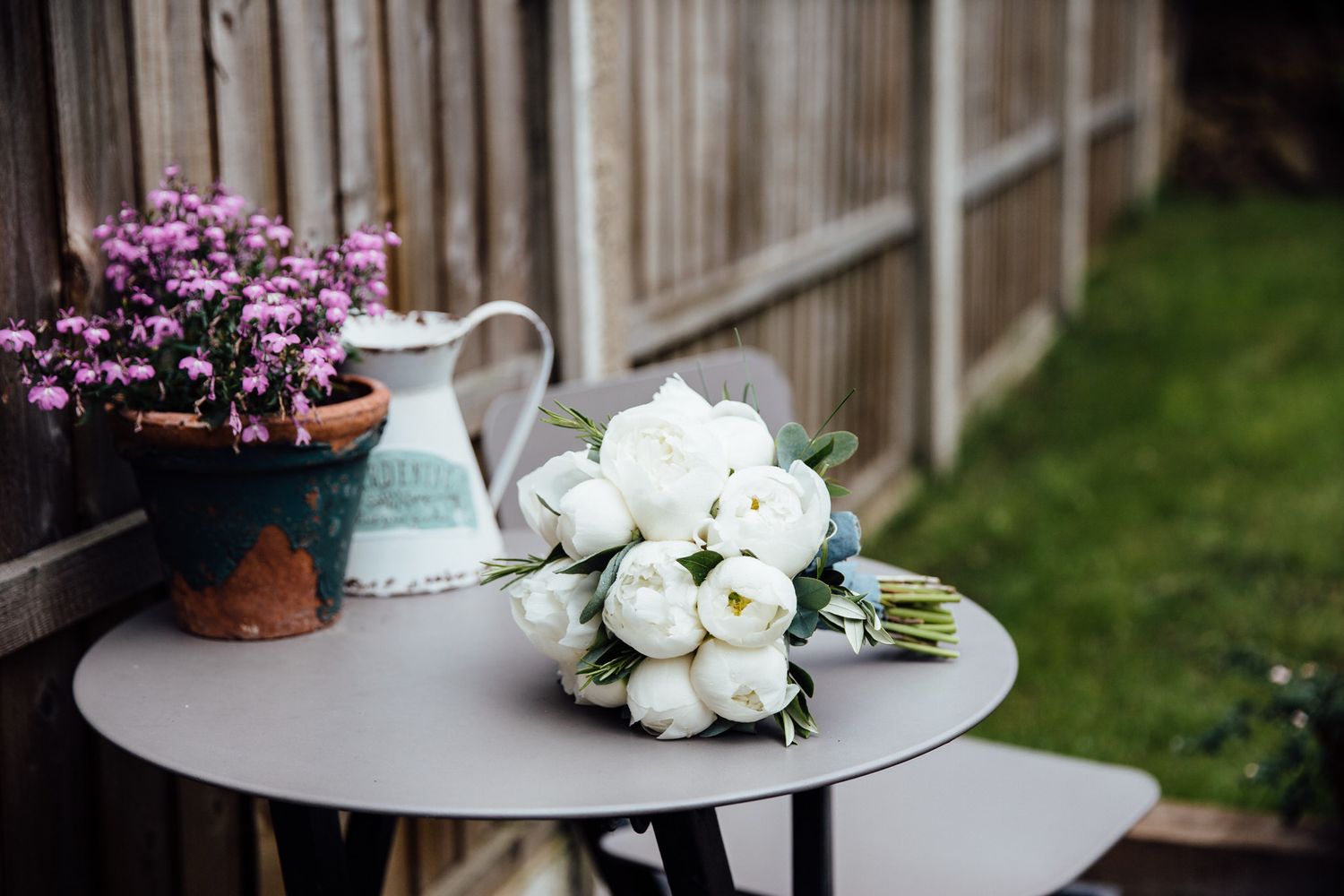 White floral arrangements and purple flowers displayed on elegant tables at a wedding reception.