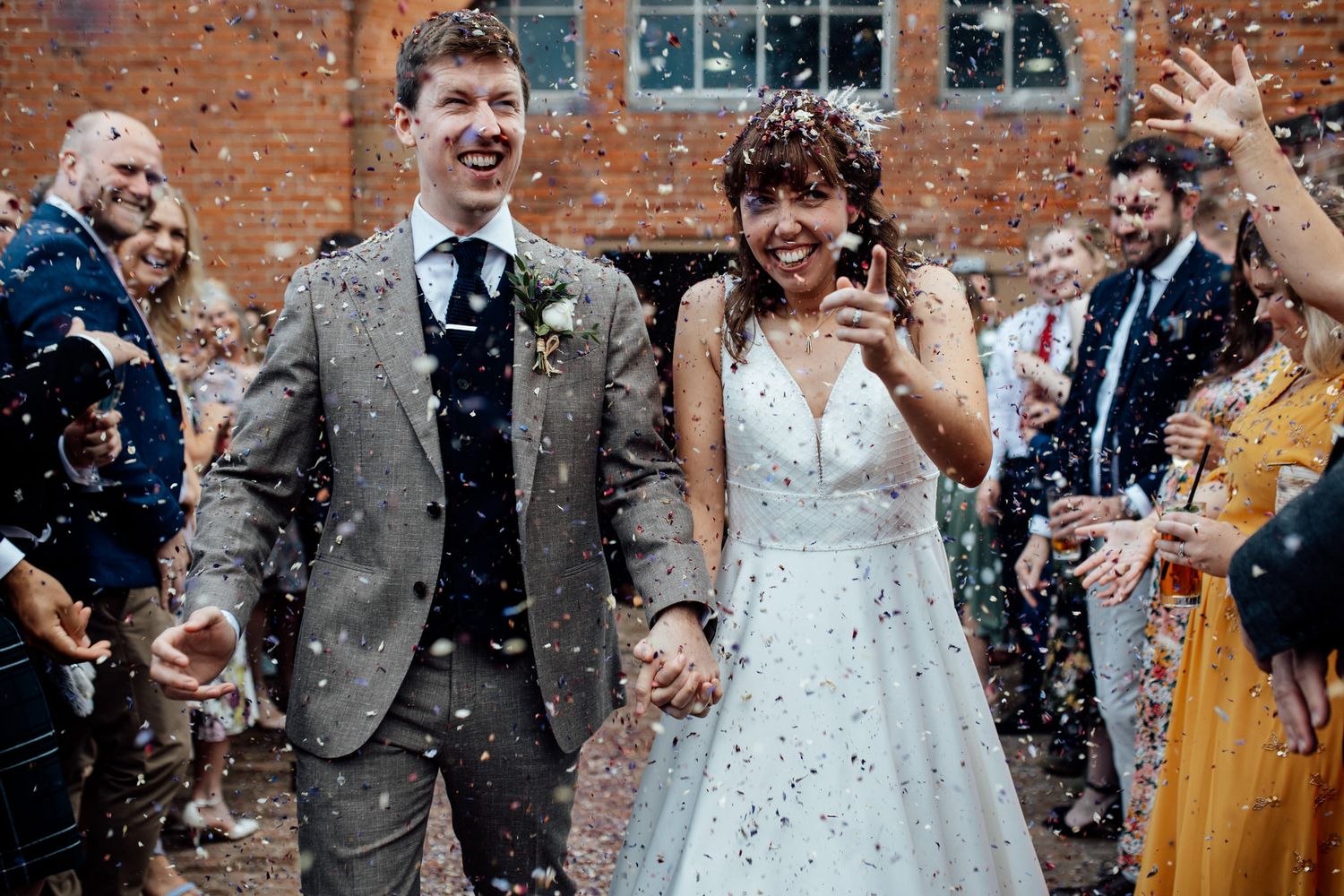 Celebratory moment with confetti at a rustic brick venue during a wedding celebration.
