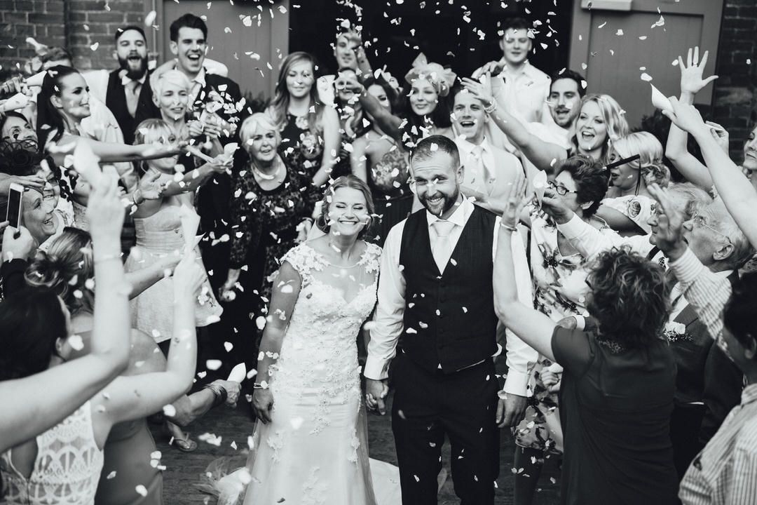 Wedding guests shower a happy couple with confetti during a joyous outdoor celebration.