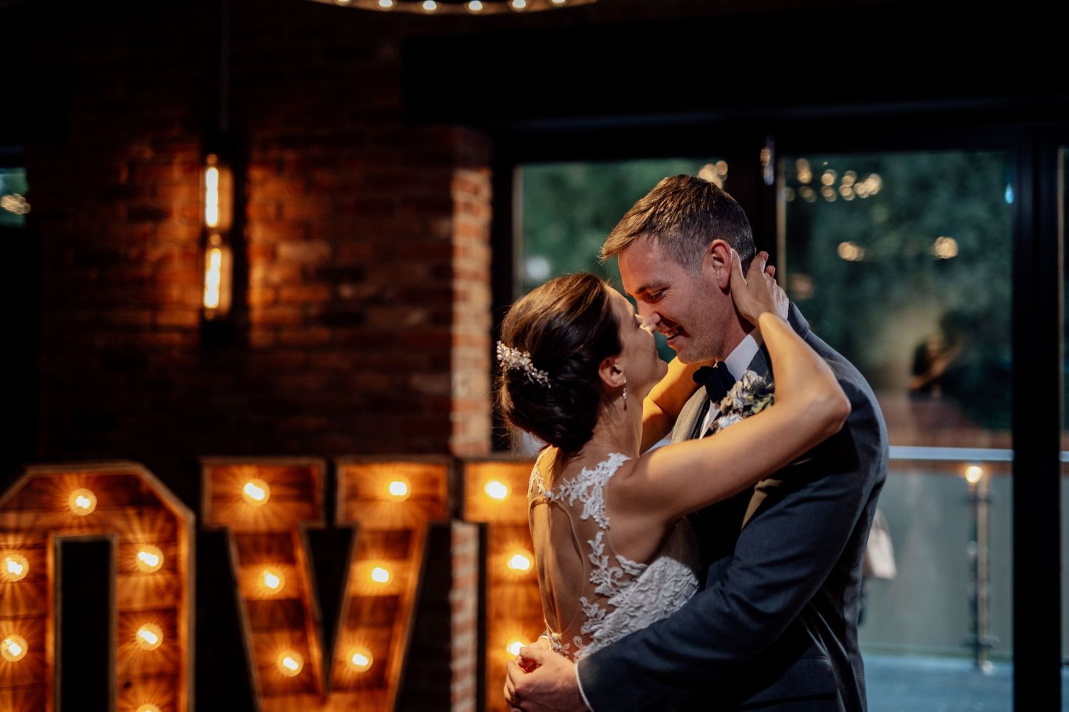 Romantic dance moment in a dimly lit venue with string lights creating ambiance.