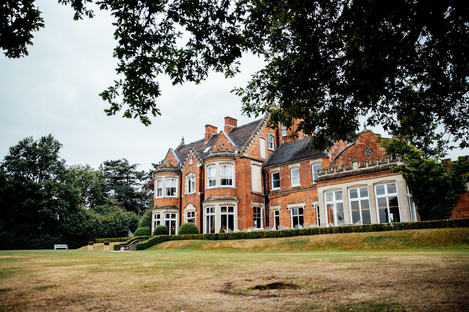 Panoramic view of a grand brick mansion with manicured grounds and classic architecture.