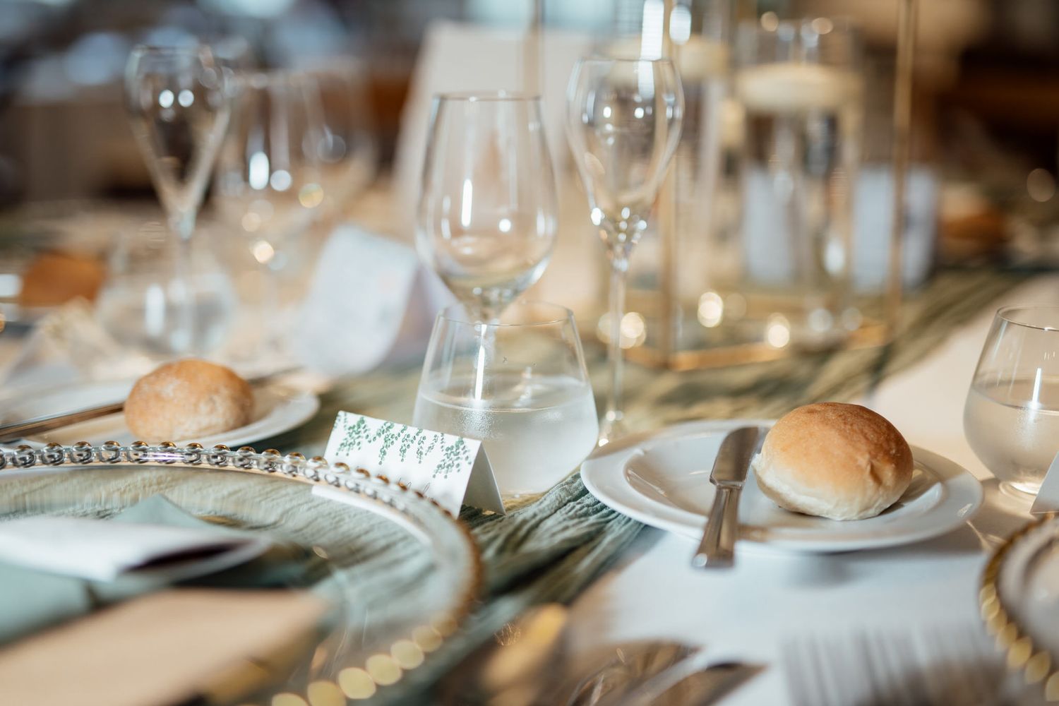 Close-up of formal place settings with wine glasses at wedding reception.