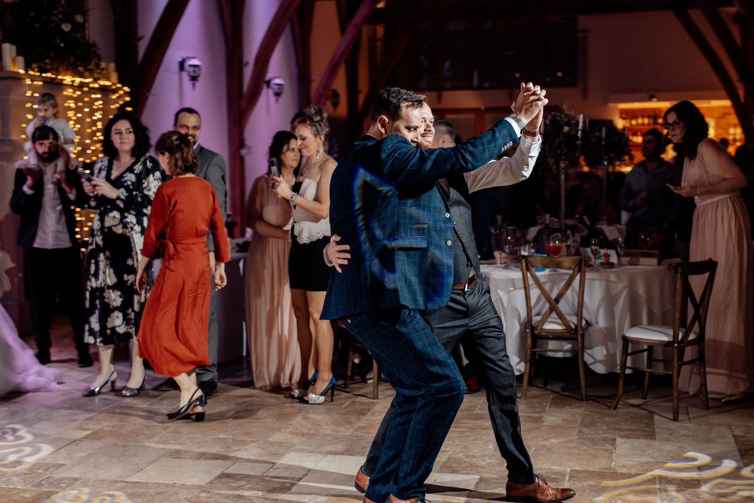 Wedding guests dancing and celebrating on a dimly lit dance floor at an elegant reception venue.
