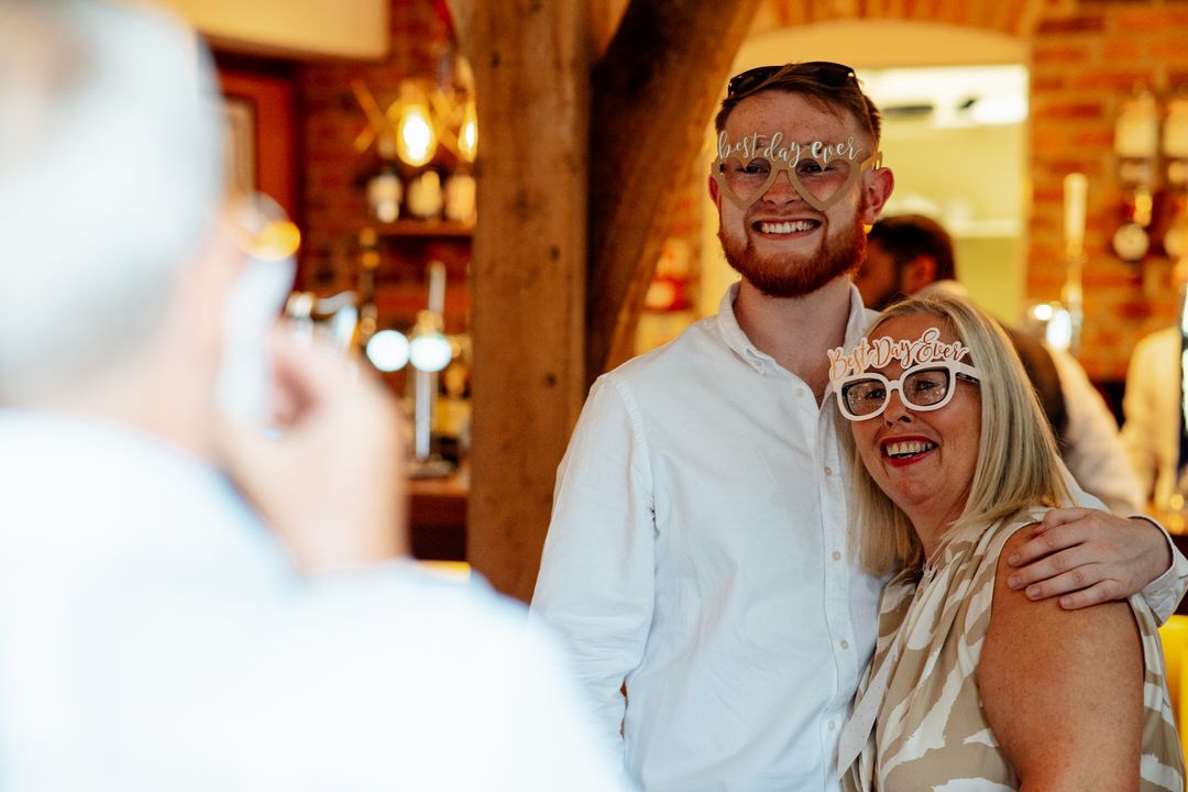 Wedding reception celebration in rustic venue with exposed wooden beams and warm lighting.