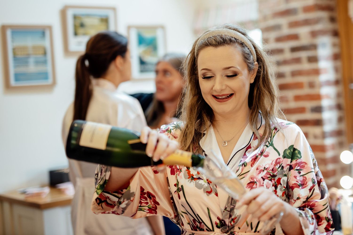 Wedding guests enjoying refreshments at a rustic brick-walled venue with natural lighting.