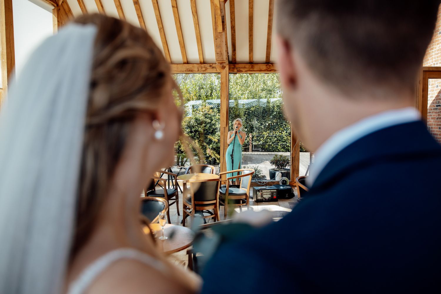 A tender moment between newlyweds in a rustic venue with wooden ceiling beams.