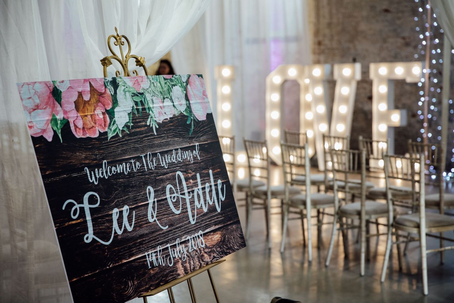 Wedding venue decorated with fairy lights and rustic chalkboard signage.