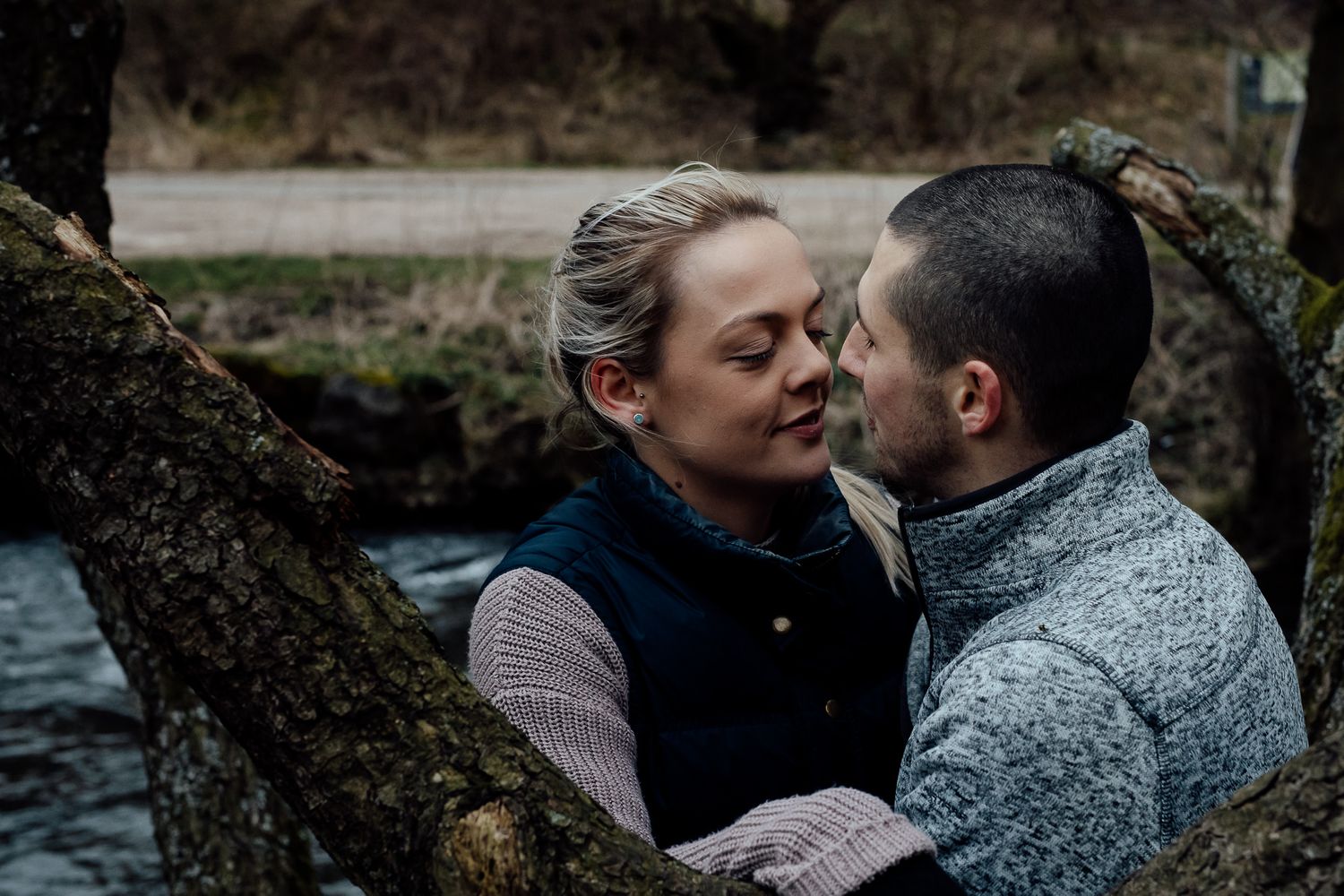 A couple embracing in a romantic moment against a dark natural background.