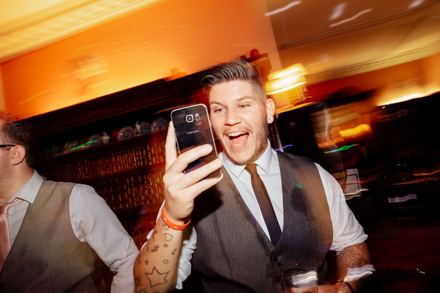 Lively reception party moments captured in warm ambient lighting.
