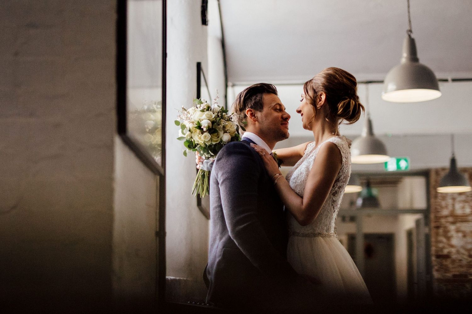 Romantic silhouette of couple dancing in minimalist venue with natural light streaming in.