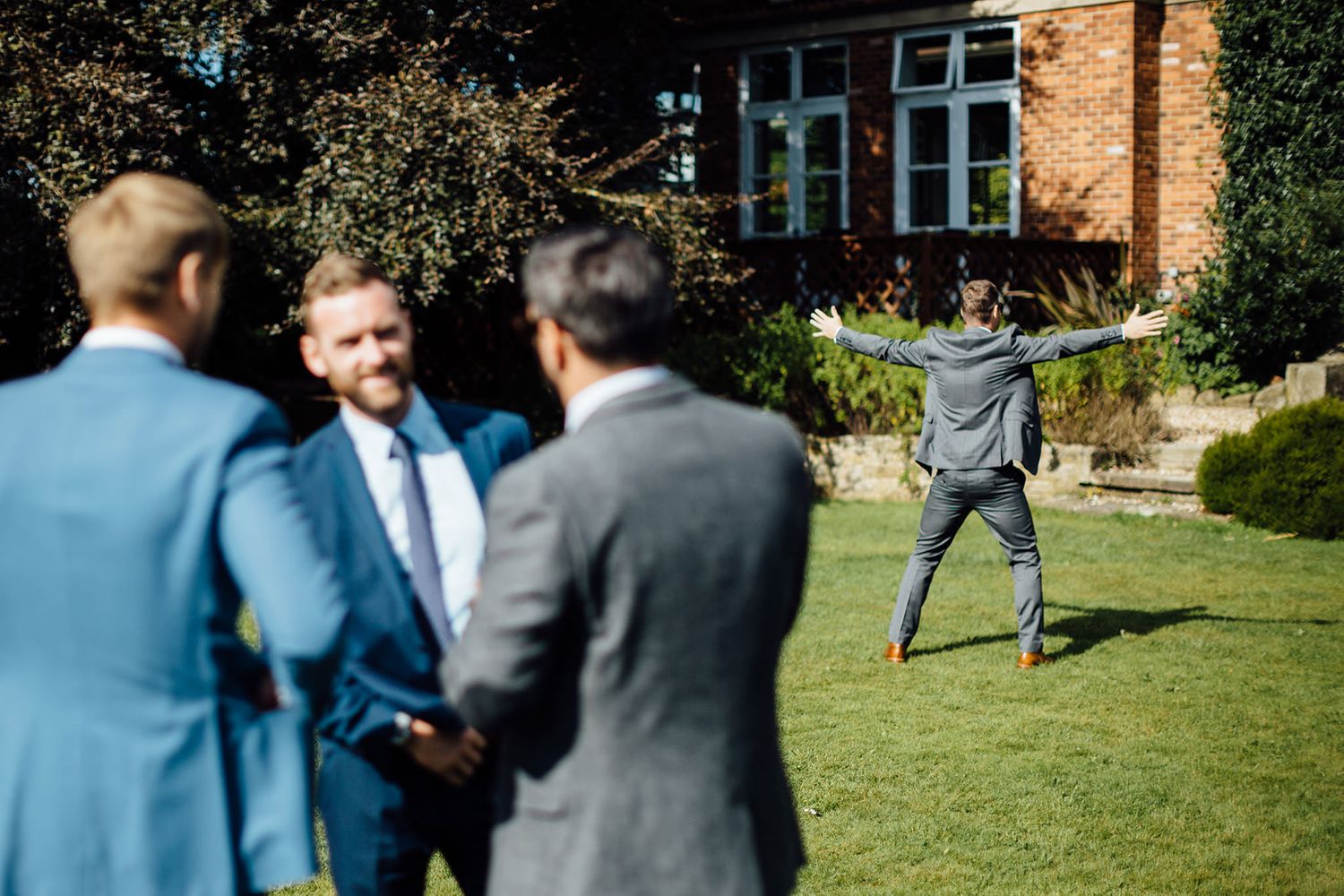 Wedding party enjoying outdoor games and activities on a sunny day at a brick venue.