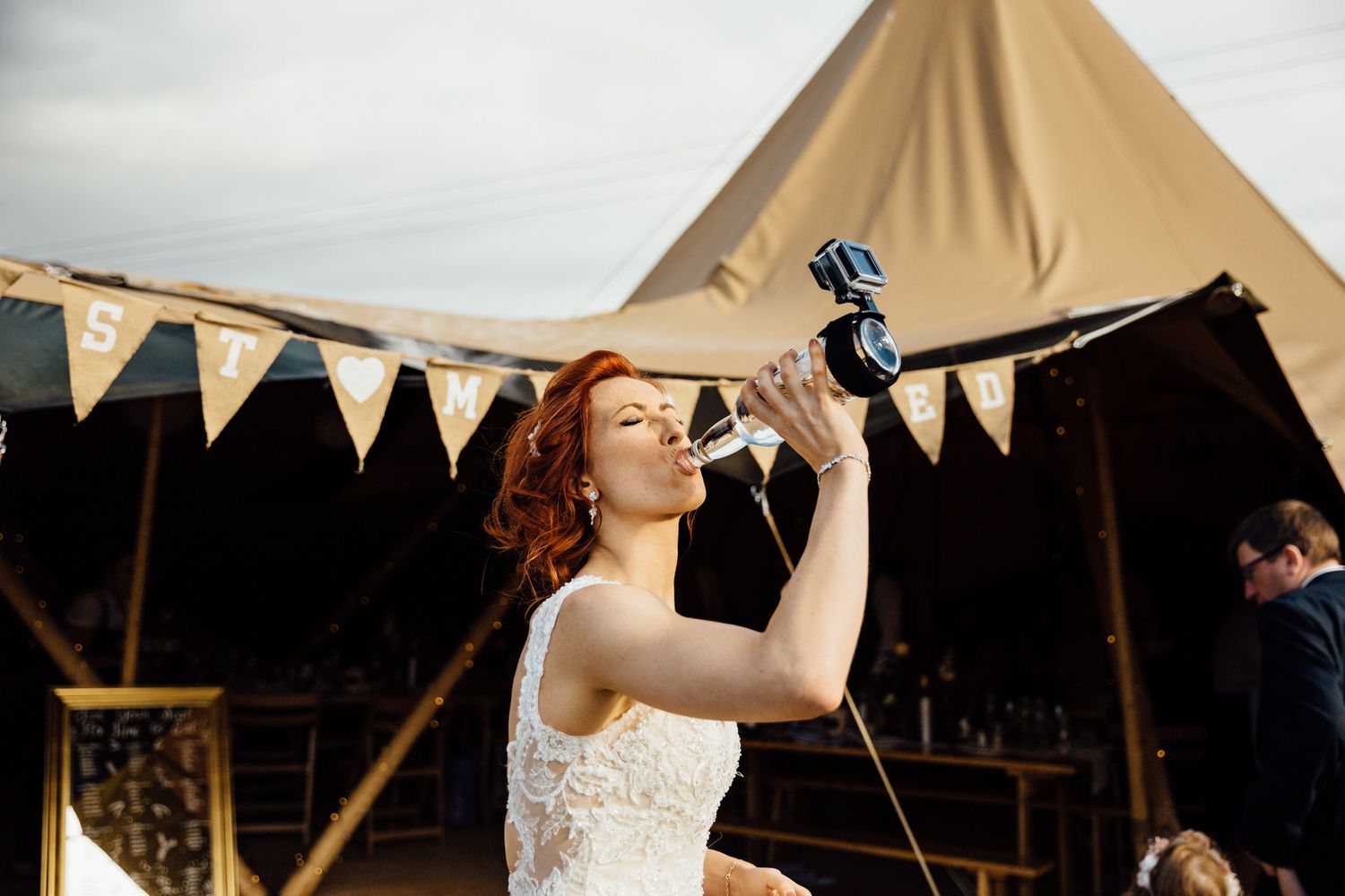Wedding celebration in a rustic tipi tent decorated with bunting and fairy lights.