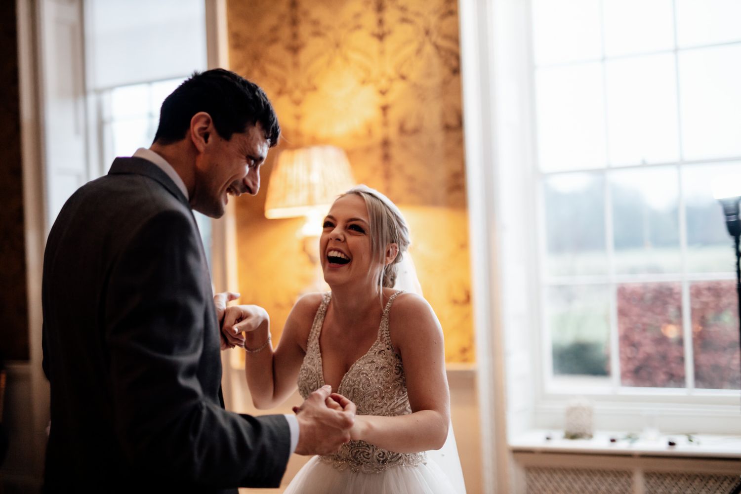 Joyful wedding celebration moments in an elegant room with large windows.