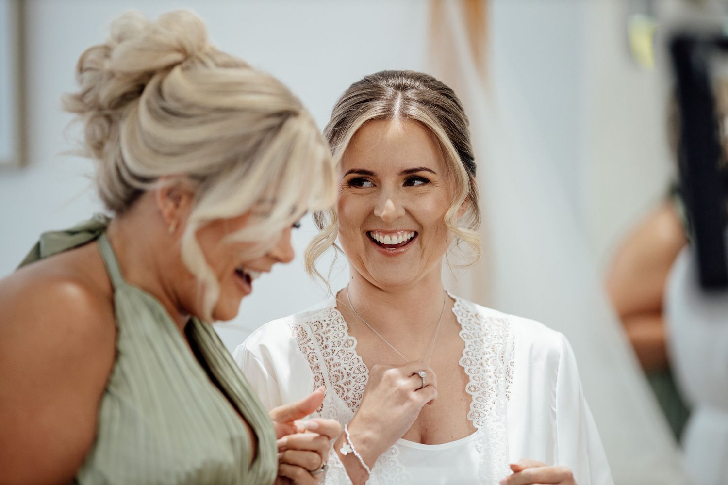 Candid moment of joy shared during wedding preparation.
