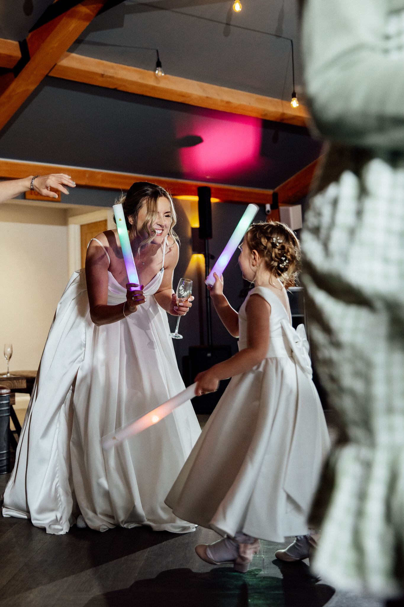 Wedding party dancing and twirling in white dresses during an indoor celebration.