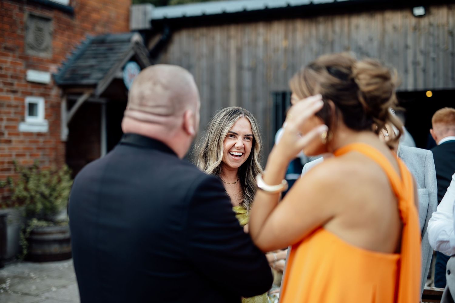 Wedding guests line up outside brick venue for celebration.