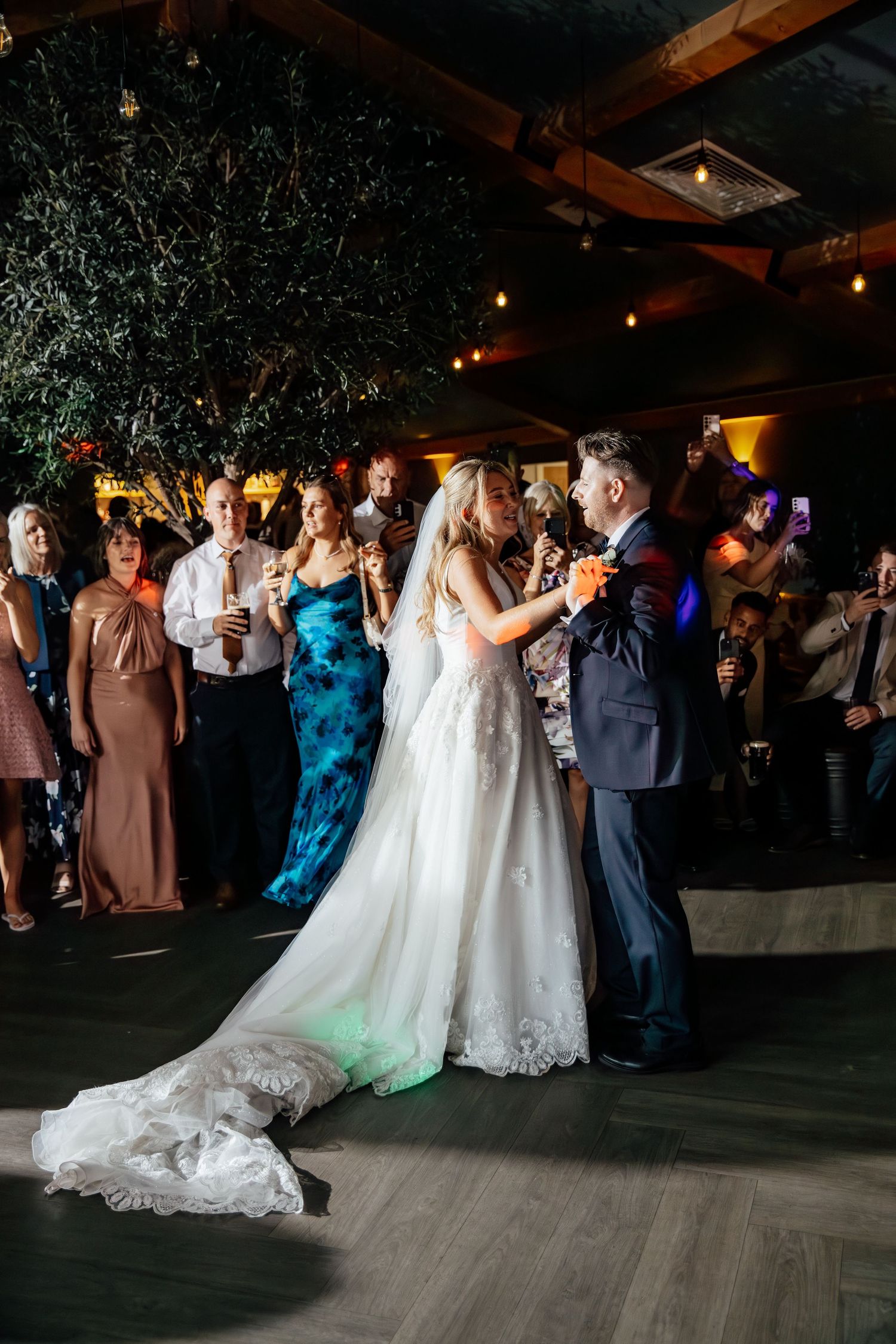 Wedding reception dance floor filled with guests celebrating under ambient lighting.
